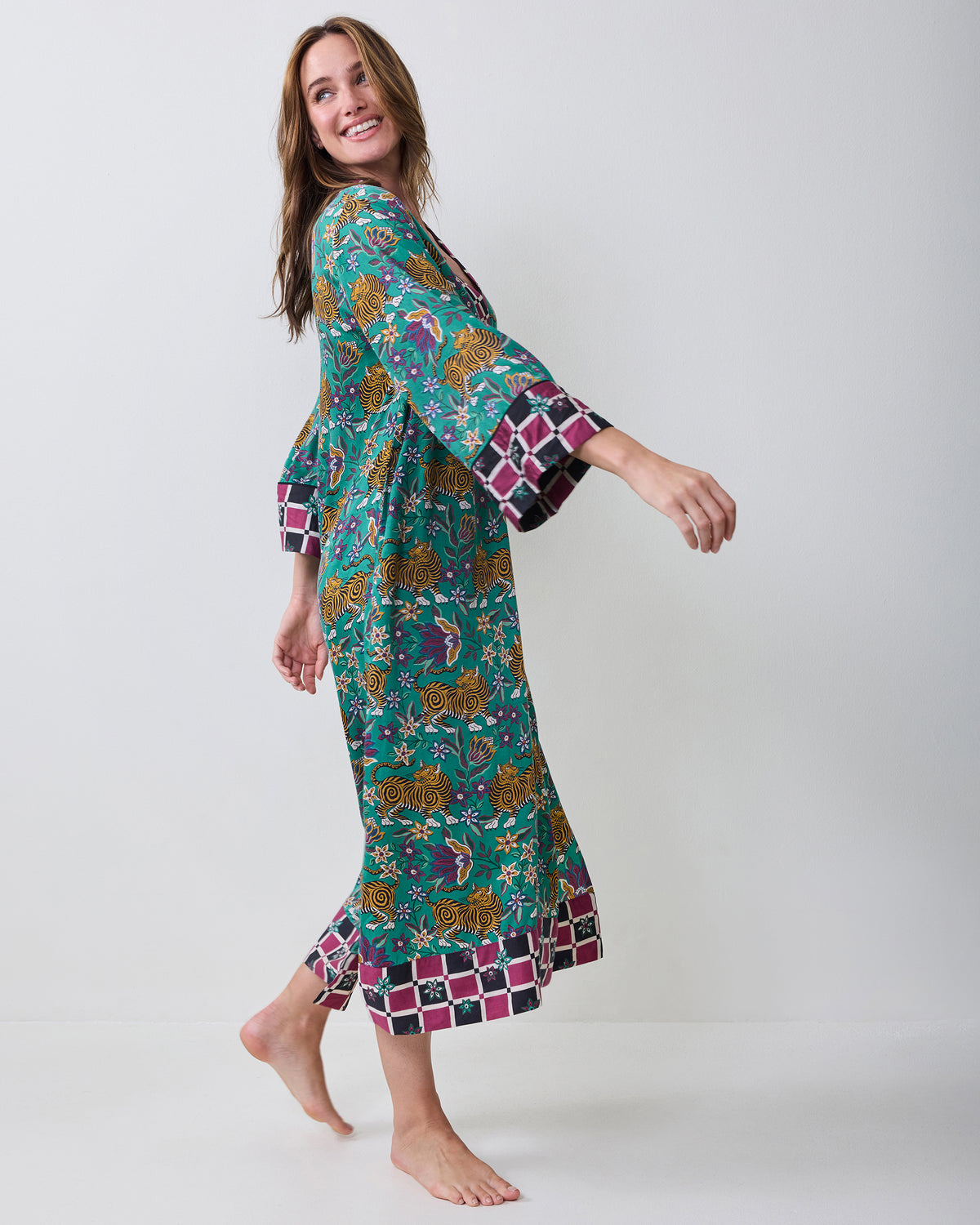 Side view of the Royal Teal Tibetan Tigress caftan showing its long silhouette, tiger-and-floral print, and contrasting hem and cuffs.