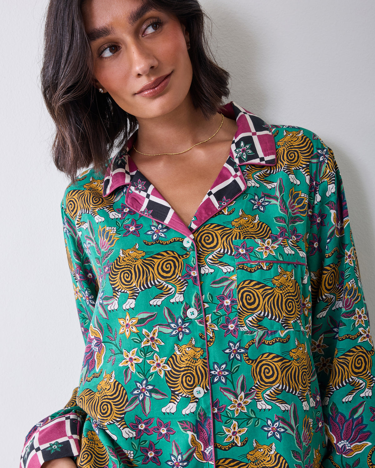 Close-up front view of the Tibetan Tigress pajama shirt showing its collar, buttons, long sleeves, teal tiger and floral print, and checked cuffs.