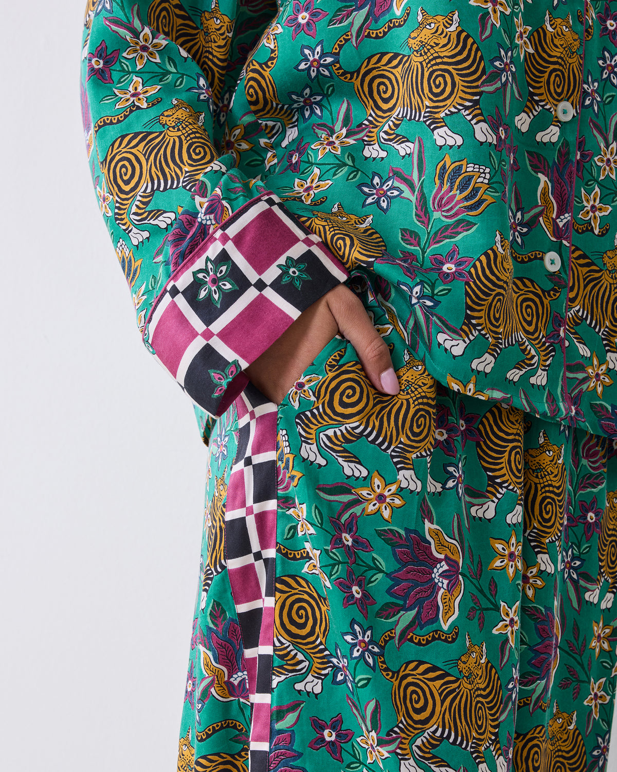 Close-up of the Tibetan Tigress pajama shirt showing the checked cuff, button, side pocket, and teal tiger and floral print.