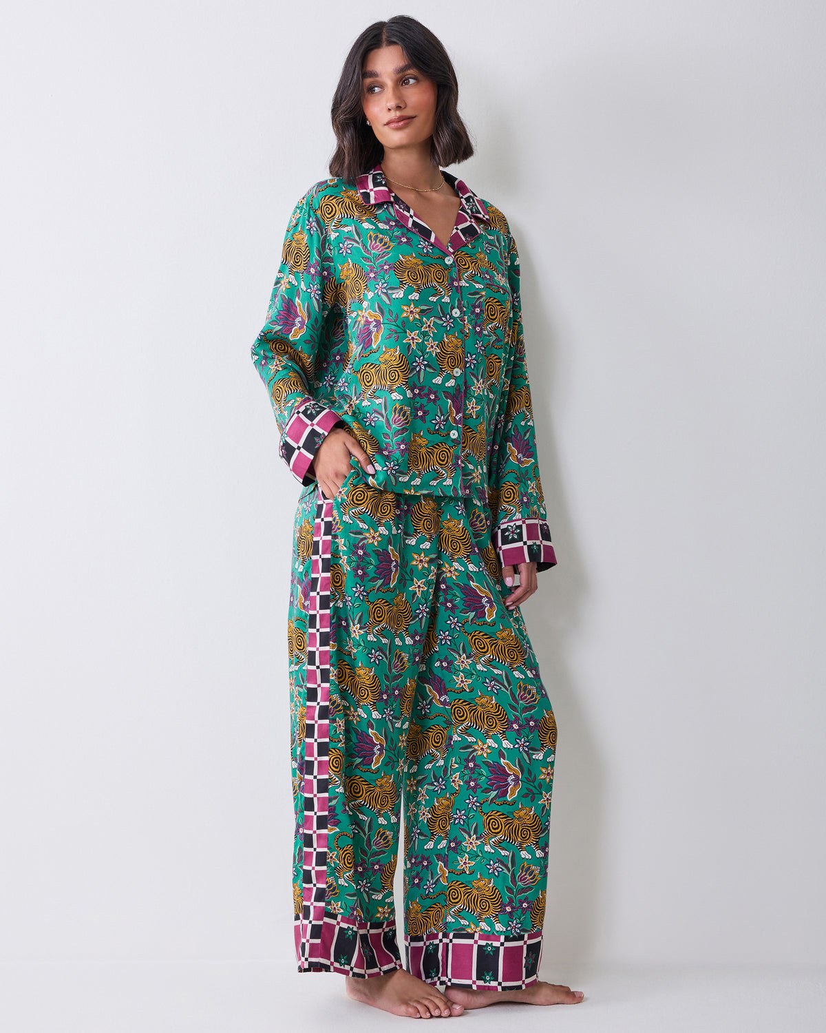 Full-length view of a person wearing the Tibetan Tigress long-sleeve pajama shirt and wide-leg pants with a teal tiger and floral print and checked trim.