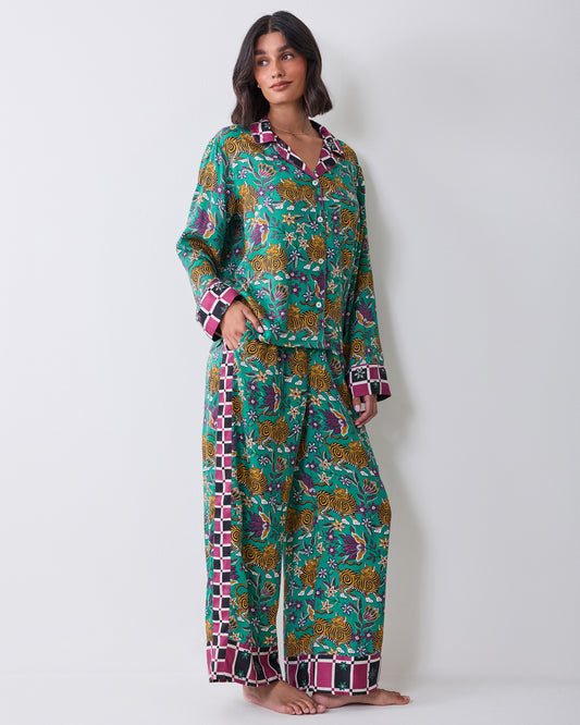 Full-length view of a person wearing the Tibetan Tigress long-sleeve pajama shirt and wide-leg pants with a teal tiger and floral print and checked trim.