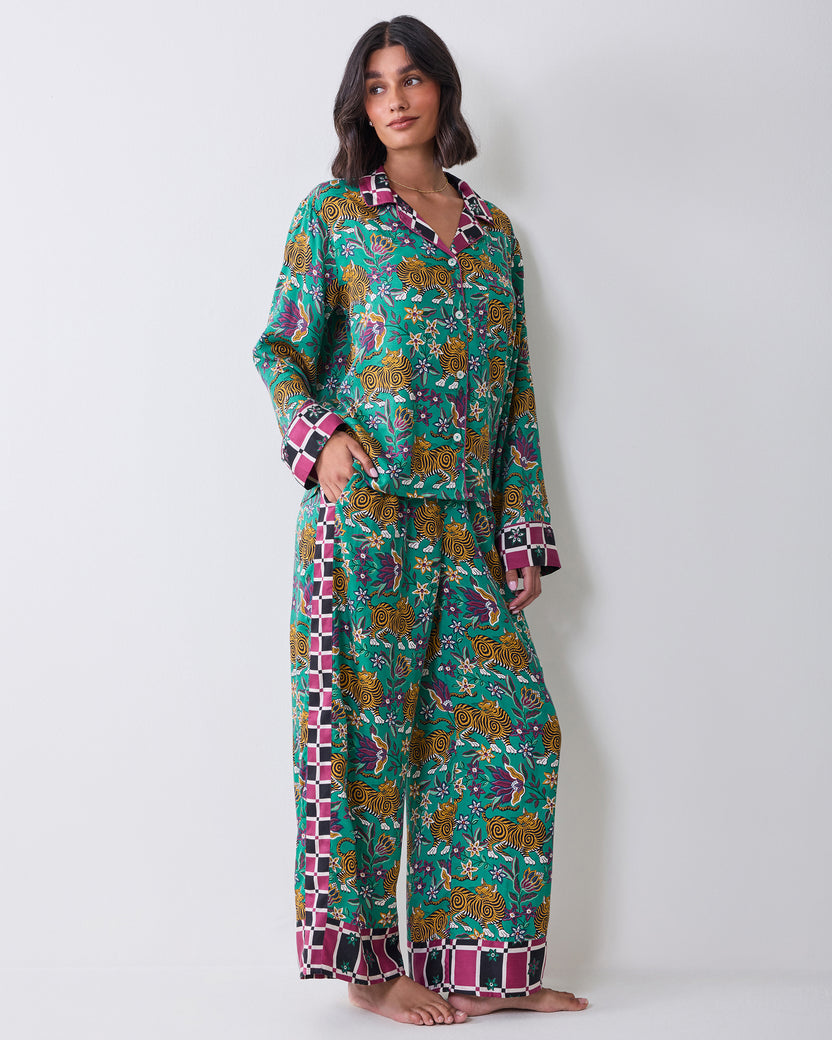 Full-length view of a person wearing the Tibetan Tigress long-sleeve pajama shirt and wide-leg pants with a teal tiger and floral print and checked trim.