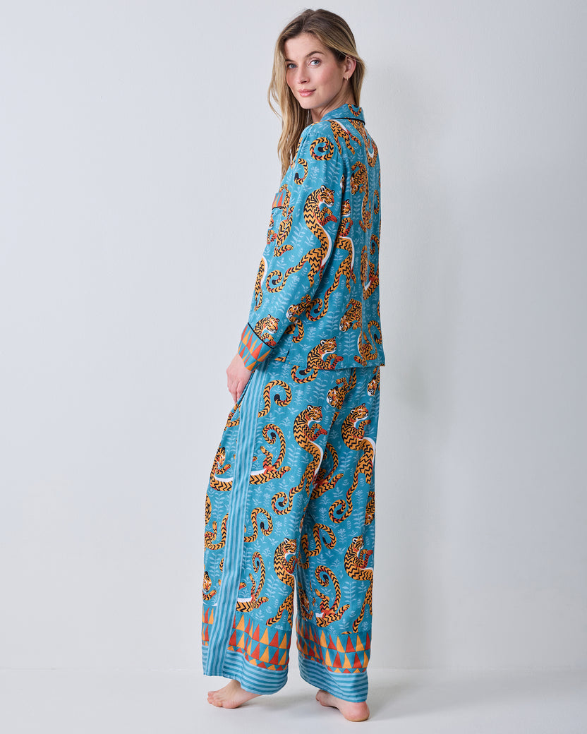 Side view of a model wearing a turquoise tiger-print button-down pajama top and wide-leg pants.