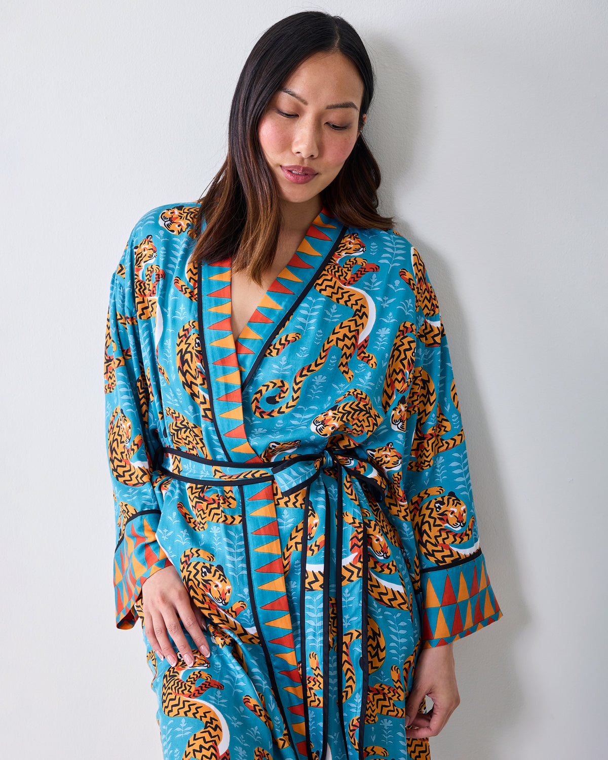 Upper-body view of a model wearing a turquoise tiger-print robe with contrasting trim and waist tie.