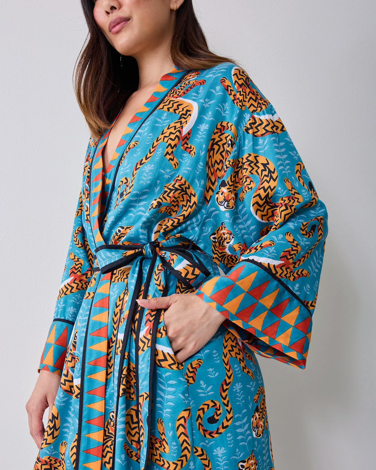 Close view of a turquoise tiger-print satin robe tied at the waist.