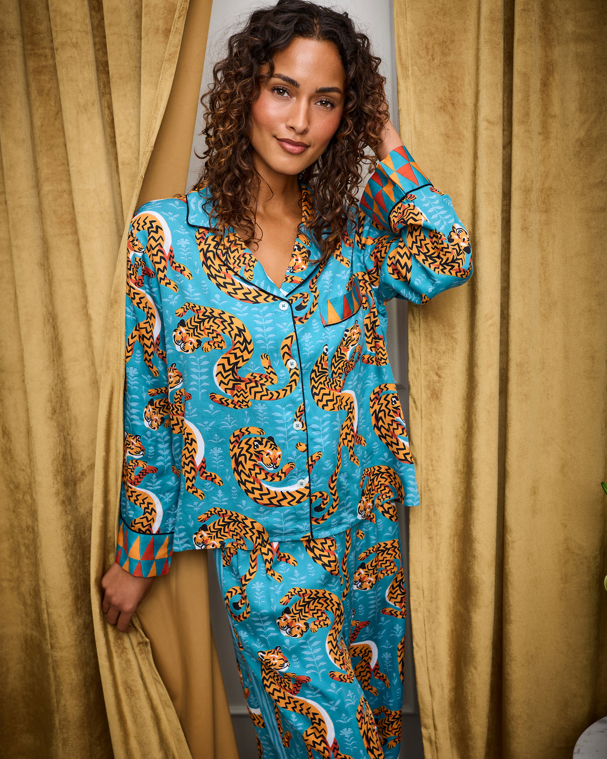 Model wearing the Persian Turquoise Twisted Tiger pajama set with a button-front top, wide-leg pants, and curled tiger print.