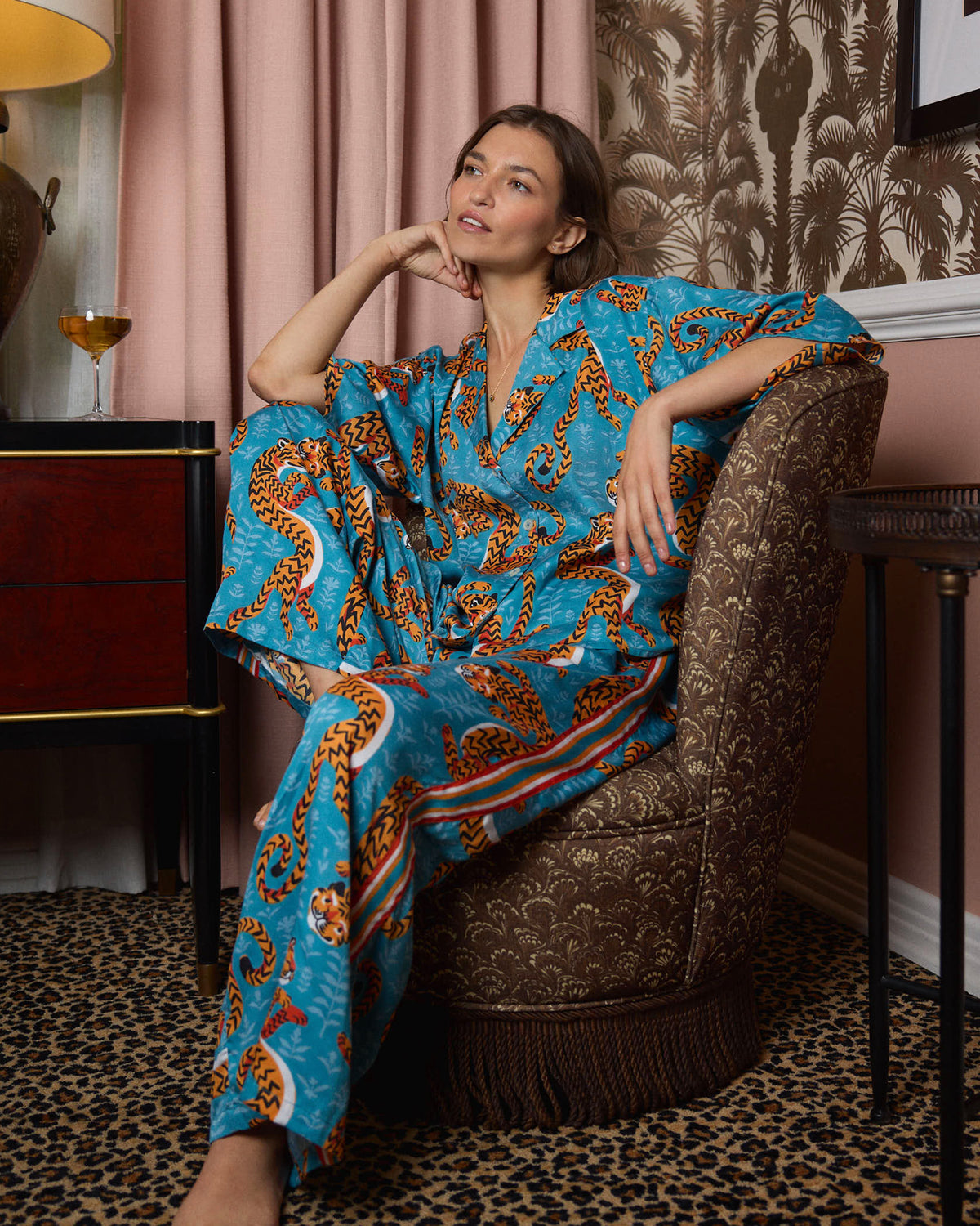 Model seated in a turquoise tiger-print pajama top and wide-leg pants.