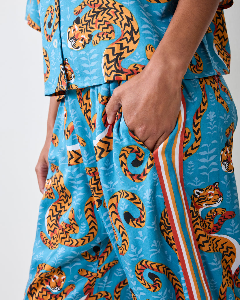 Close-up of the turquoise Twisted Tiger pajama set showing the cropped top, wide-leg pants, pocket, tiger print, and striped side trim.