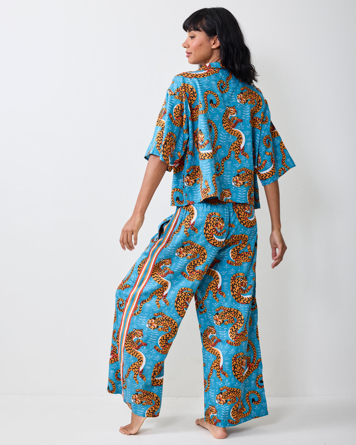 Back view of a person wearing the turquoise Twisted Tiger pajama set, showing the printed cropped top and wide-leg pants.