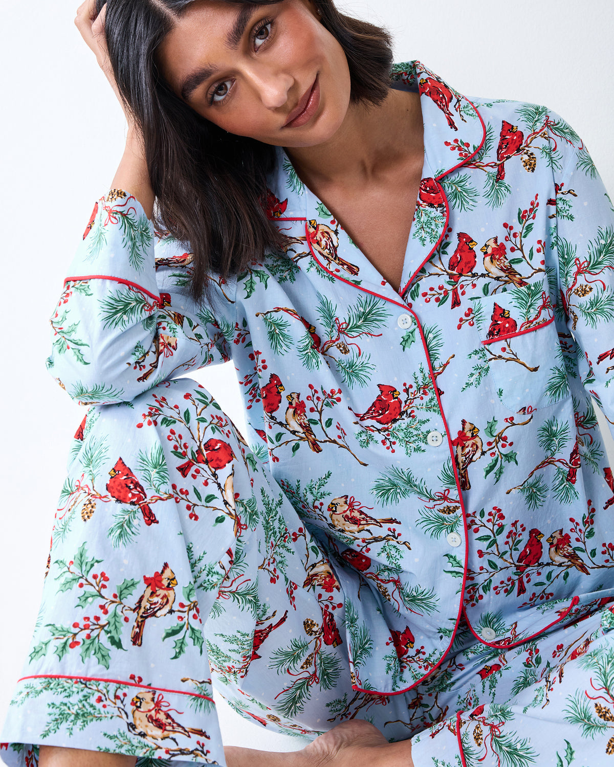 Close view of the Frosted Blue Winter Cardinals pajama set, showing the notched collar, red piping, buttons, and printed top and pants.