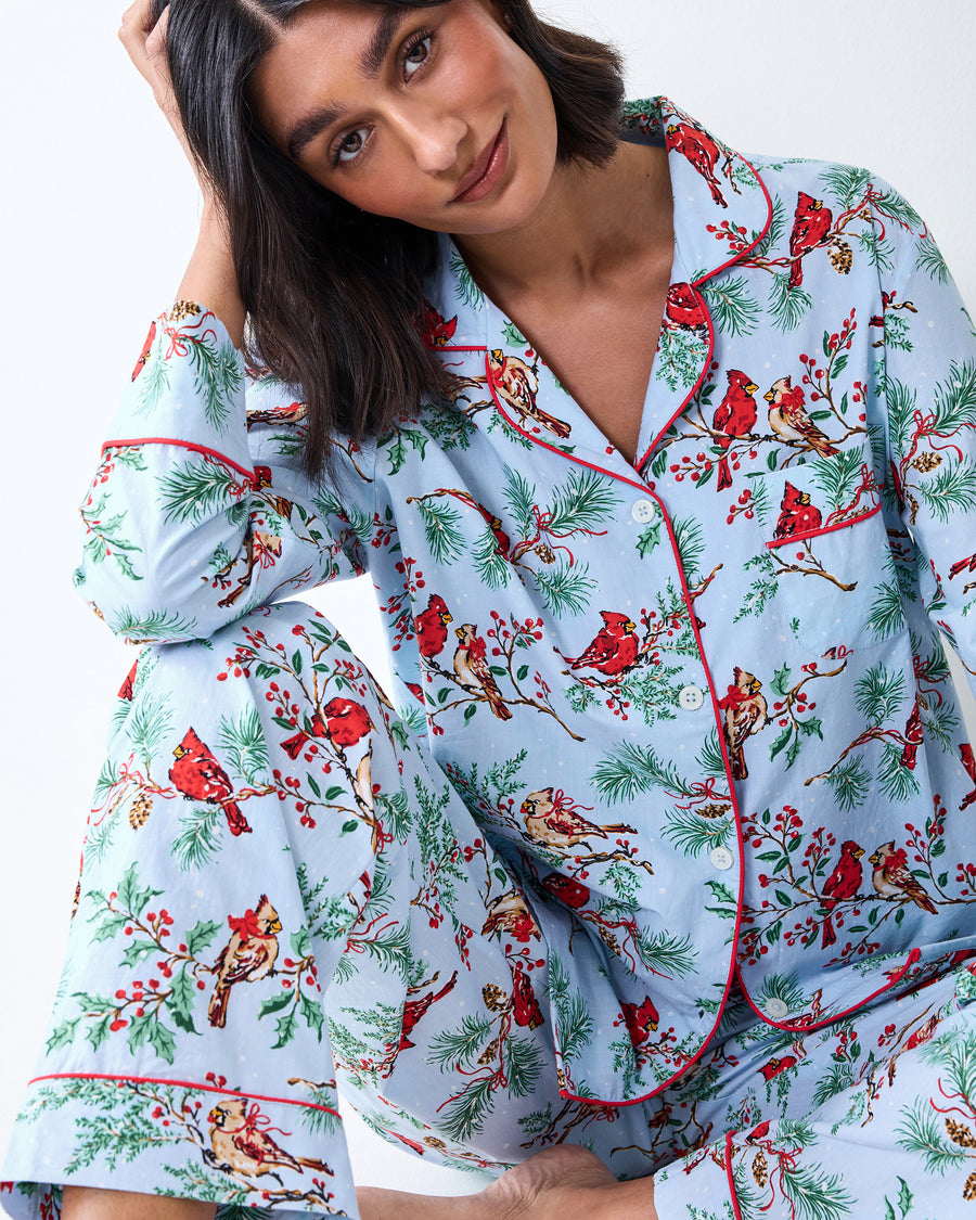 Close view of the Frosted Blue Winter Cardinals pajama set, showing the notched collar, red piping, buttons, and printed top and pants.