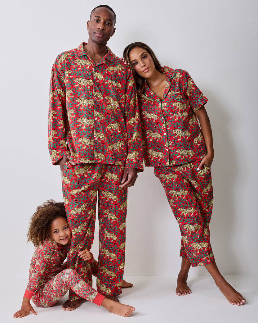 Three people modeling matching red leopard-and-holly pajama sets.