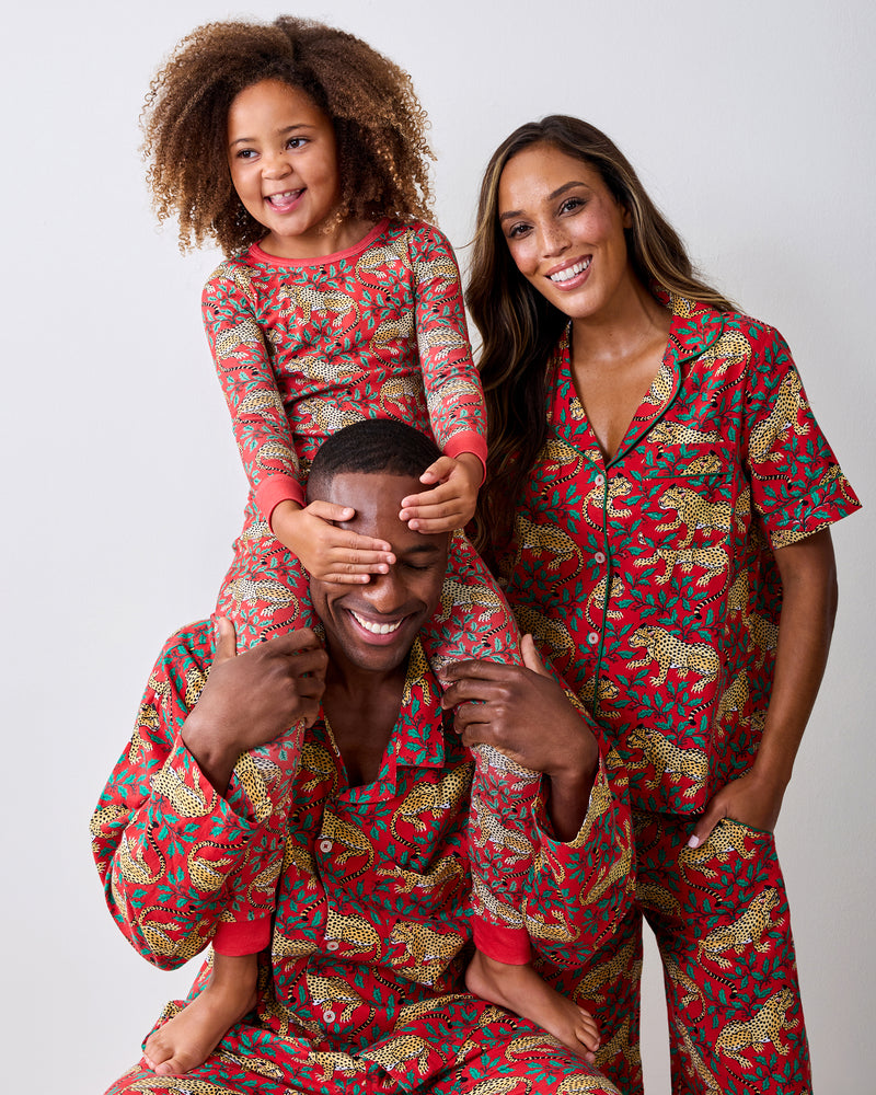 Three people pose together in matching red pajamas with leopard and leafy prints.