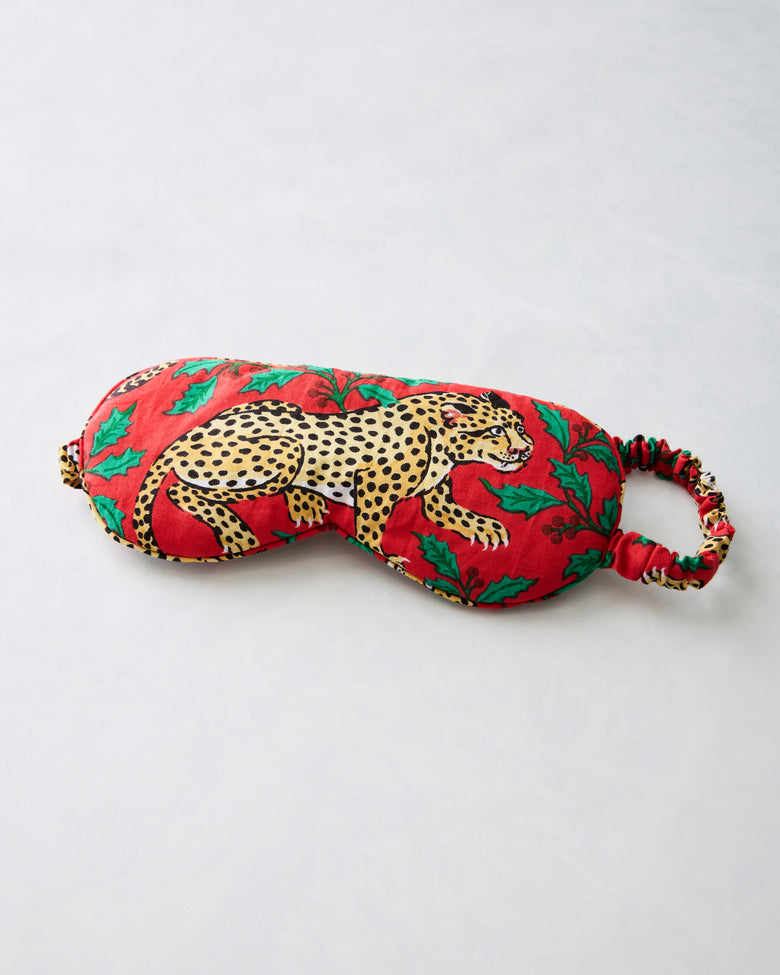 Ruby eye mask with leopard and holly print and an elastic strap, shown flat.