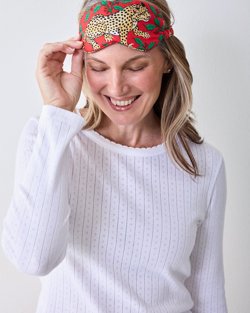 Person wearing the ruby leopard-and-holly printed eye mask raised above the eyes.
