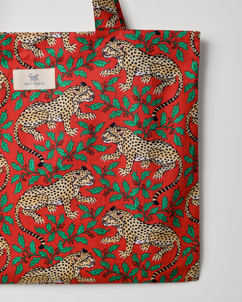 Close-up of the red Winter Holly Bagheera tote showing the leopard-and-holly print and a Printfresh label.