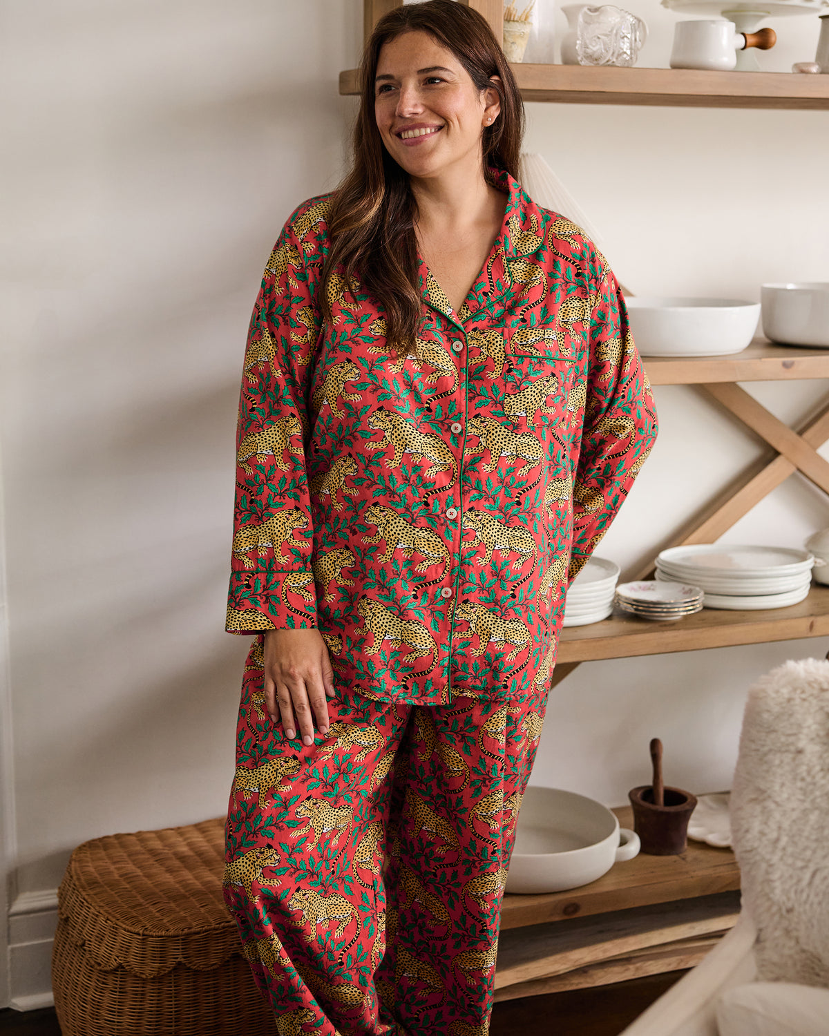 Person wearing a ruby Winter Holly Bagheera long pajama set stands indoors in front of open shelving.