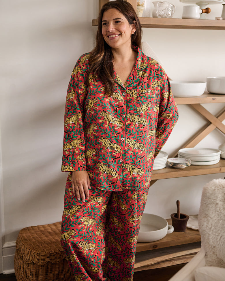 Person wearing a ruby Winter Holly Bagheera long pajama set stands indoors in front of open shelving.
