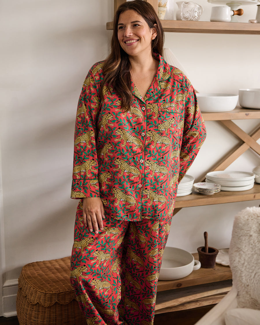 Person wearing a ruby Winter Holly Bagheera long pajama set stands indoors in front of open shelving.