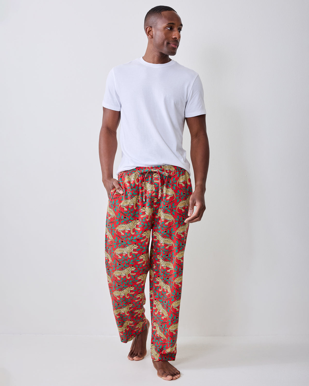 Front view of red pajama pants with a repeating leopard-and-leaf print, worn with a white T-shirt.