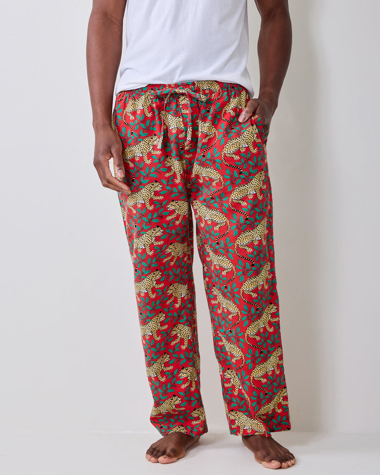 Close front view of red pajama pants with a repeating leopard-and-leaf print and drawstring waist.