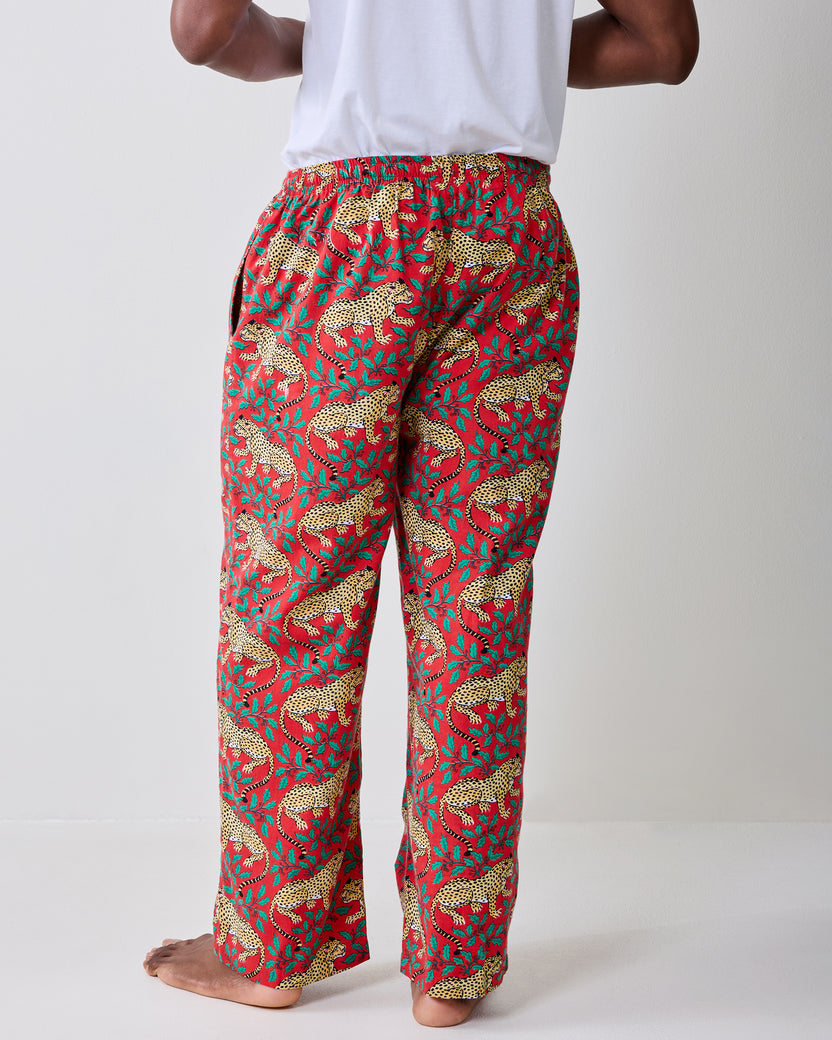 Close back view of red pajama pants with a repeating leopard-and-leaf print and elasticized waist.