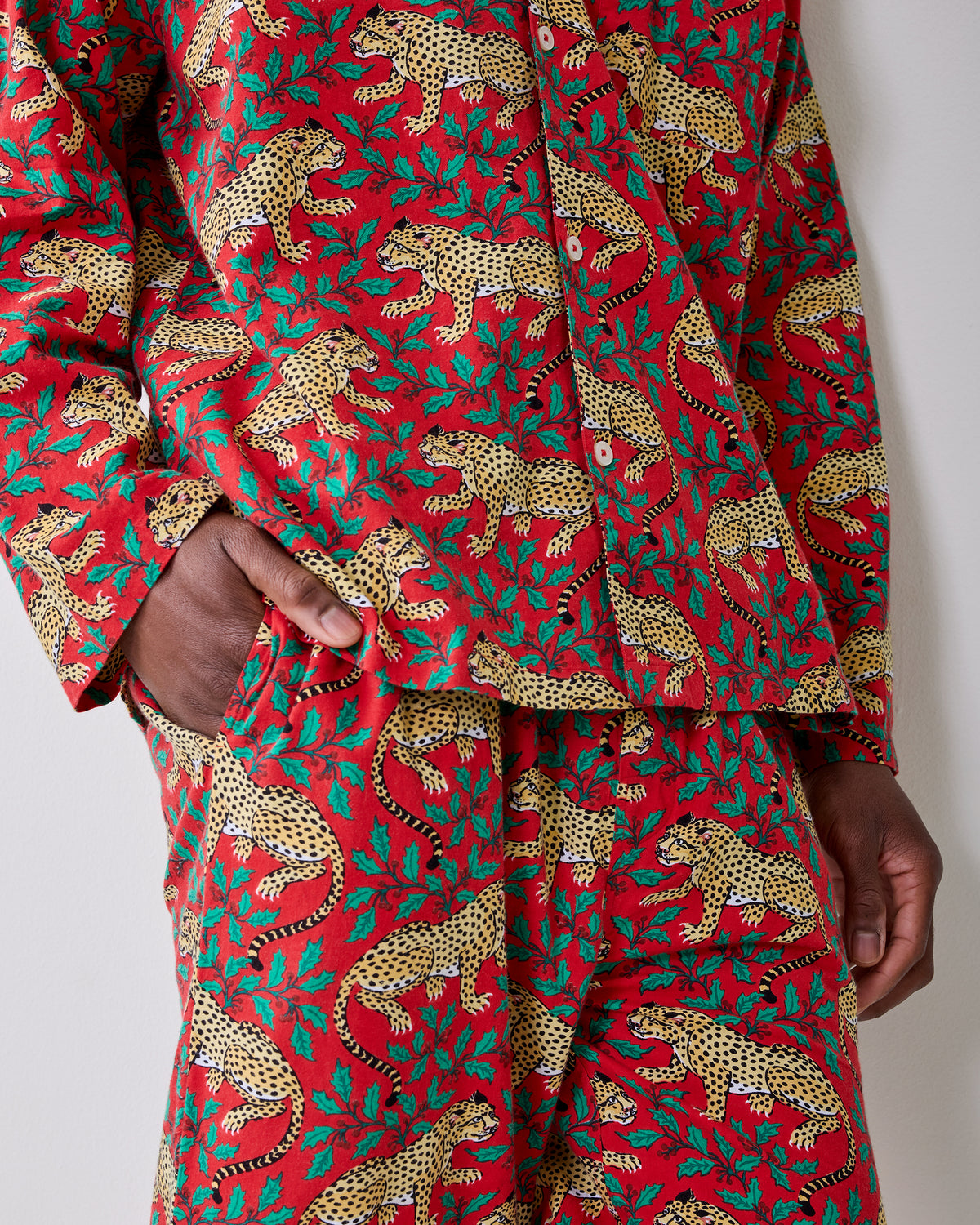Close-up of the red leopard-and-holly pajama shirt and pants, showing the print and side pockets.