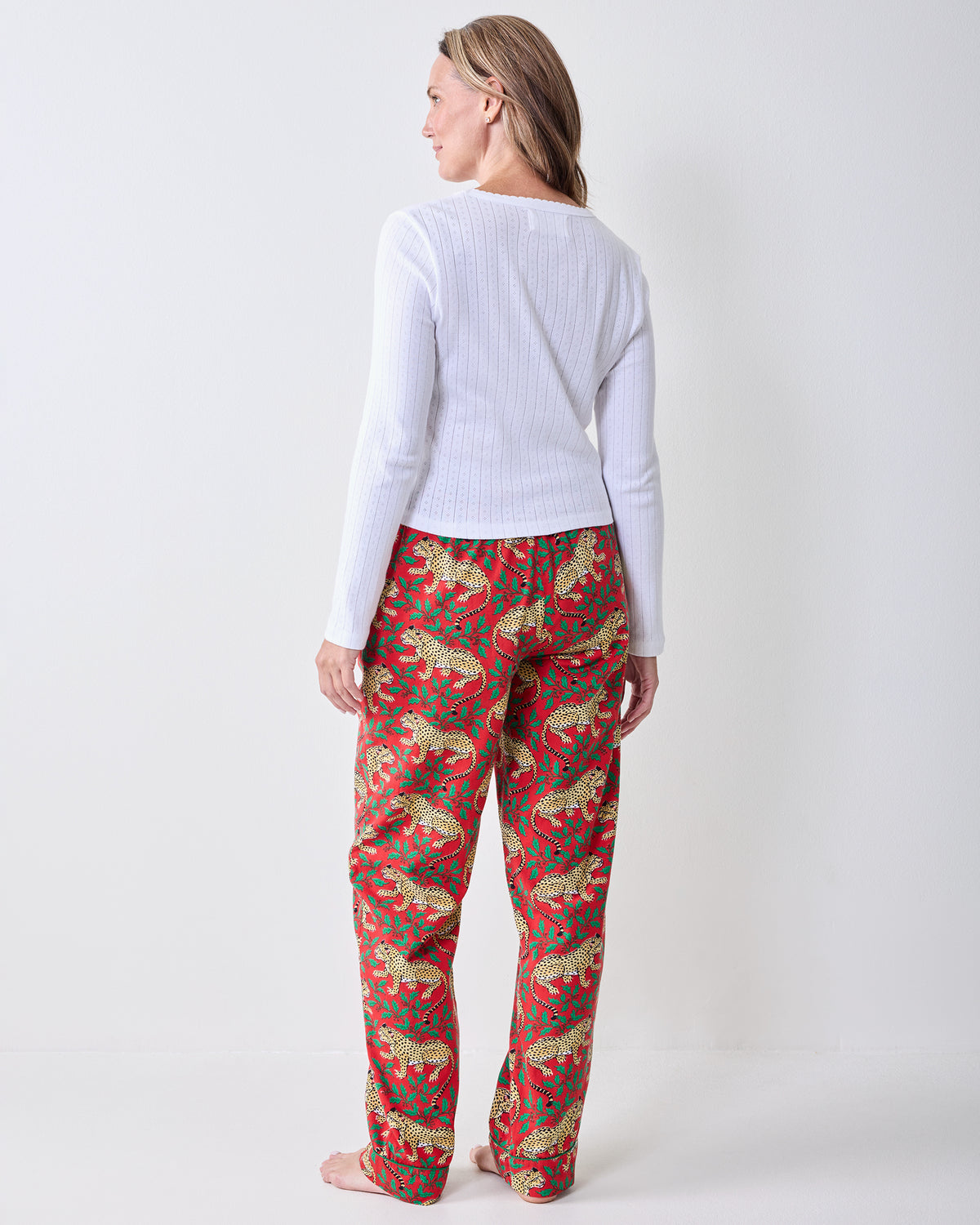 Back view of Winter Holly Bagheera pajama pants showing the full-length legs and red leopard-and-holly print.