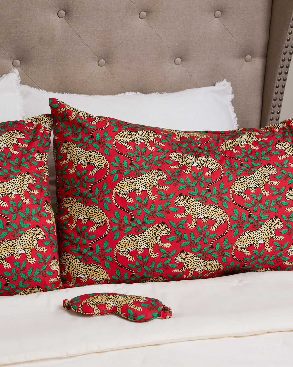 Winter Holly Bagheera patterned pillowcases arranged on a bed with a matching small fabric item in the foreground.