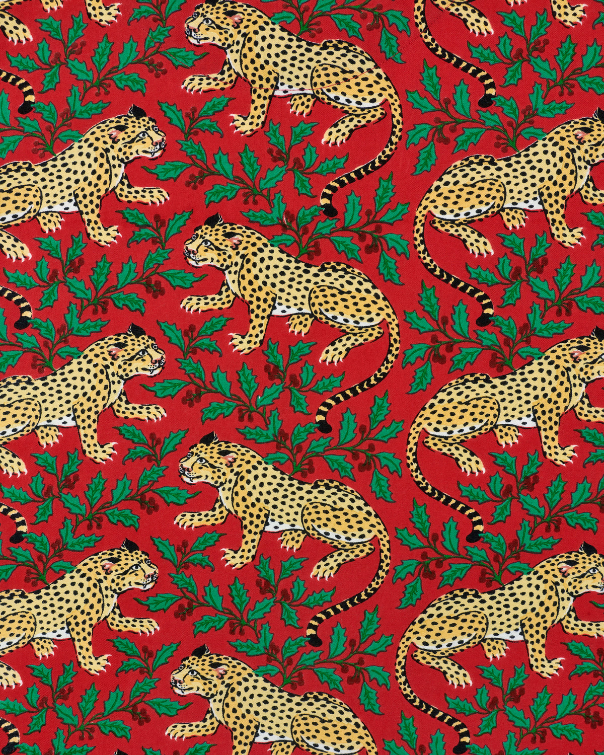 Red fabric print featuring repeated spotted leopards and green holly leaves.