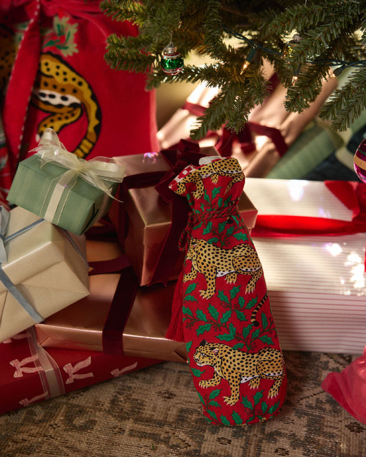Winter Holly Bagheera ruby wine bag displayed beside wrapped gifts under a Christmas tree.