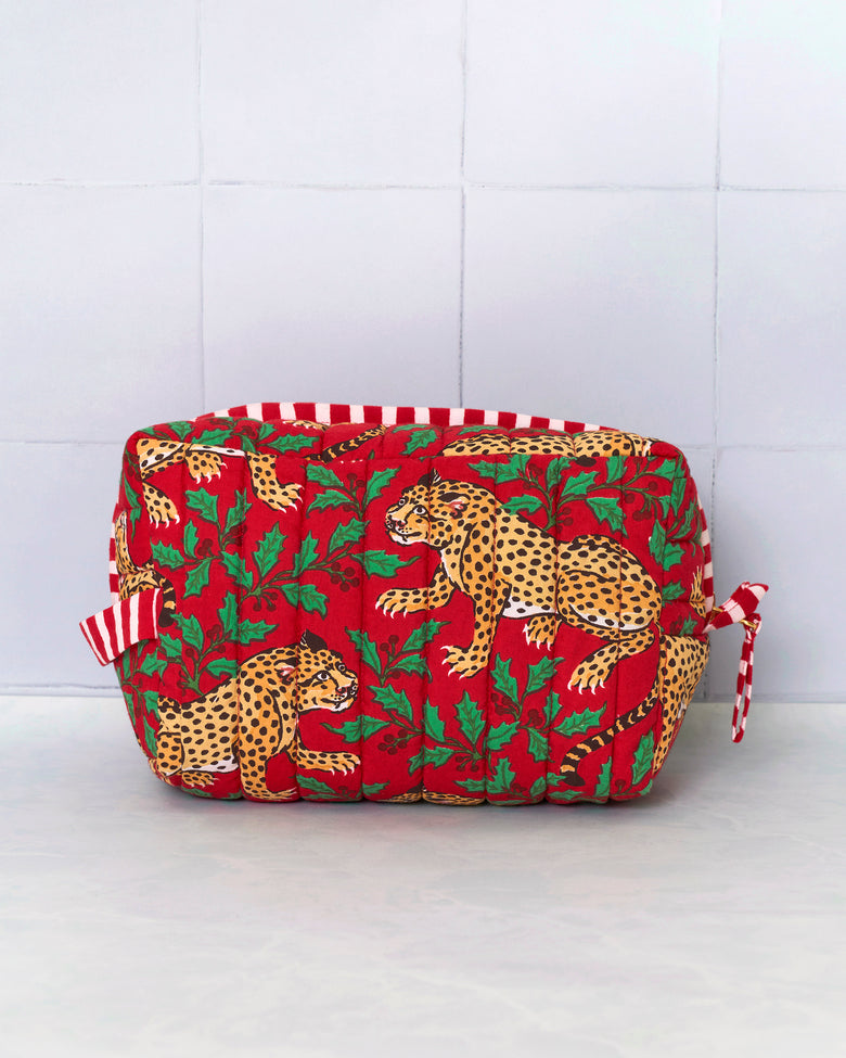 Front view of the Winter Holly Bagheera quilted pouch showing its leopard-and-holly pattern and side ties.