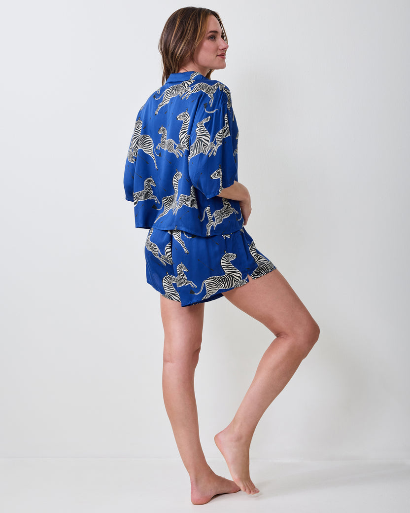 Person modeling a blue zebra-print short-sleeve pajama top and shorts set, shown from the back.