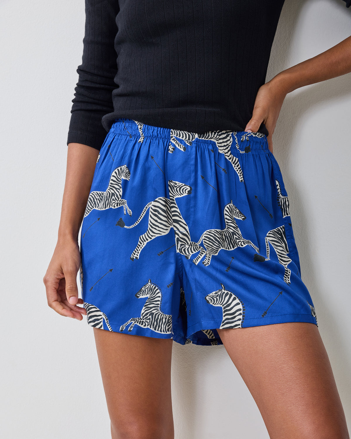 Close-up of a model wearing blue boyfriend boxer shorts with a zebra-and-arrow print.