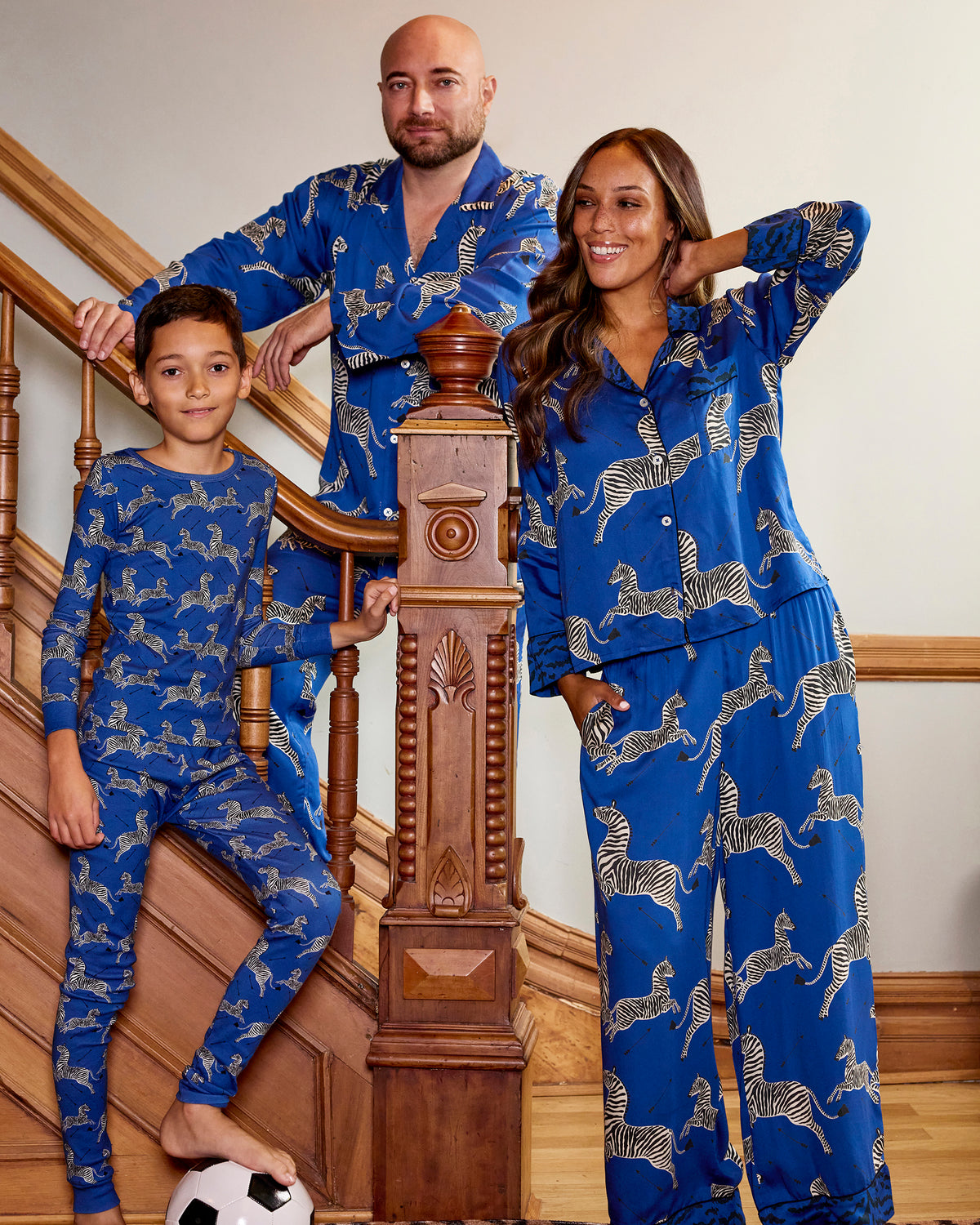 Family group wearing matching blue pajamas with white zebra prints on a staircase.