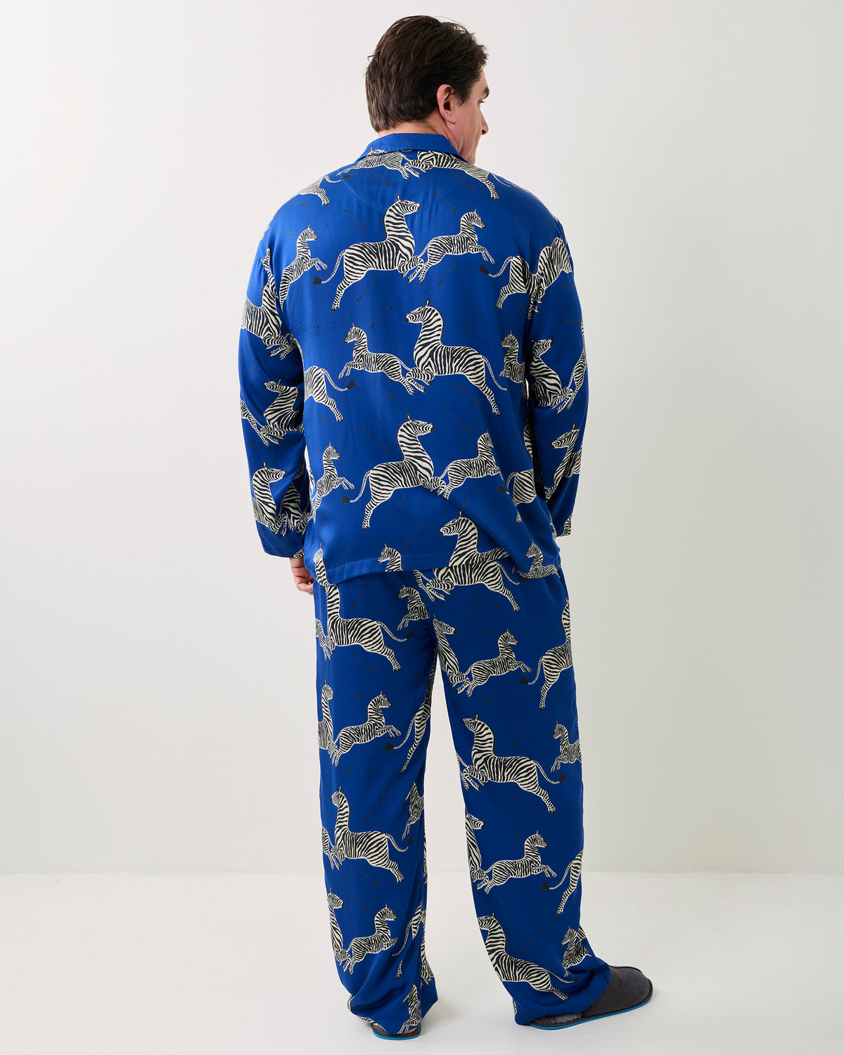 Back view of a person wearing a blue long-sleeve pajama top and matching pants with zebra print.