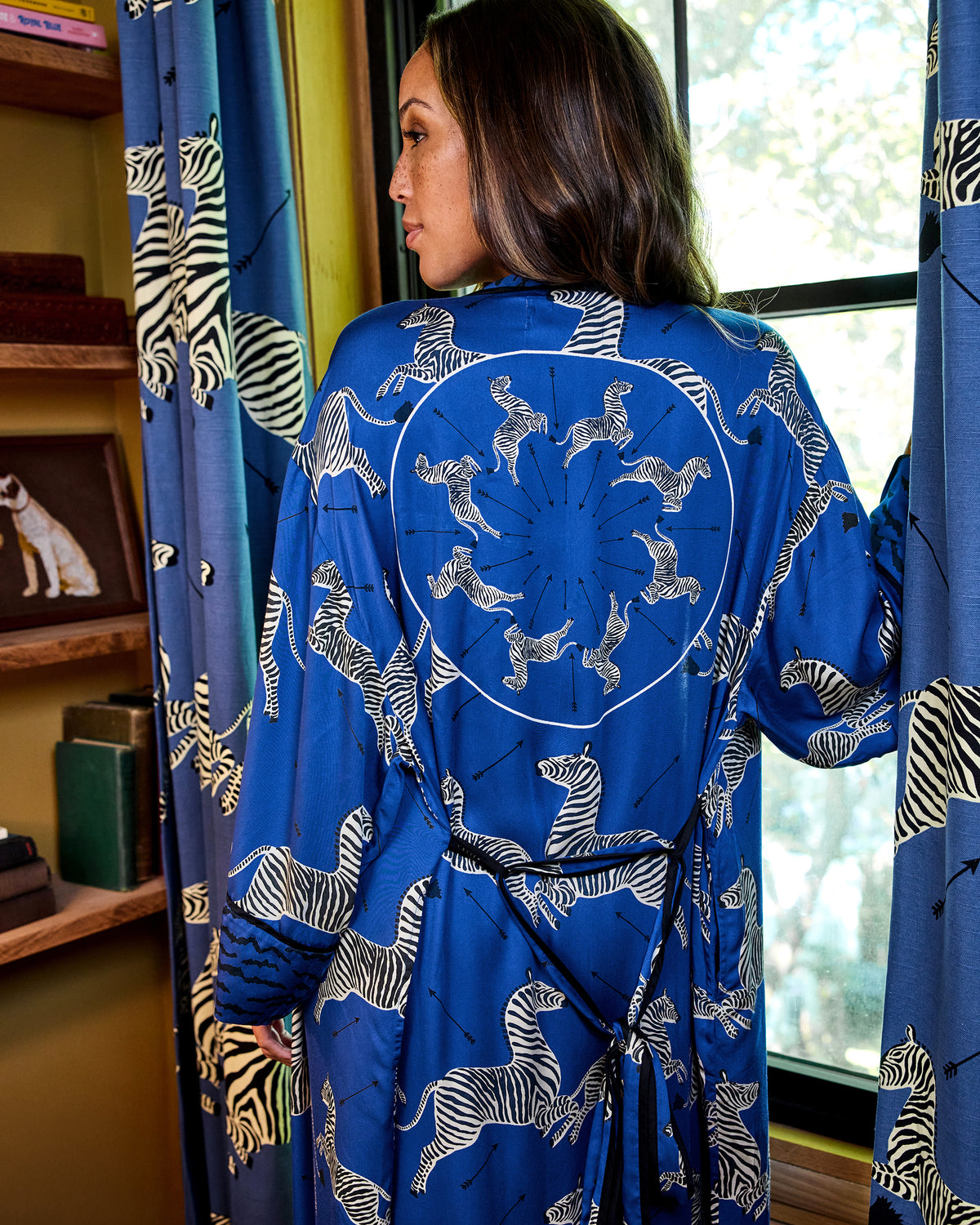Back view of a blue zebra-print robe with a circular zebra motif and tied belt.