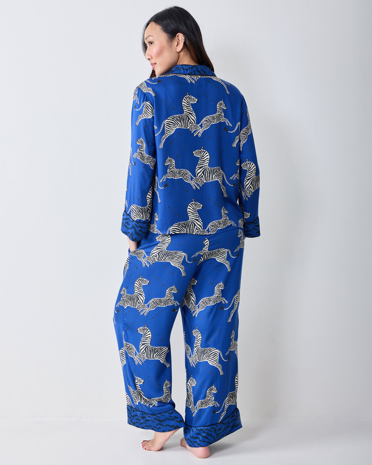 Rear view of a person wearing a blue zebra-print long-sleeve pajama shirt and wide-leg pants.
