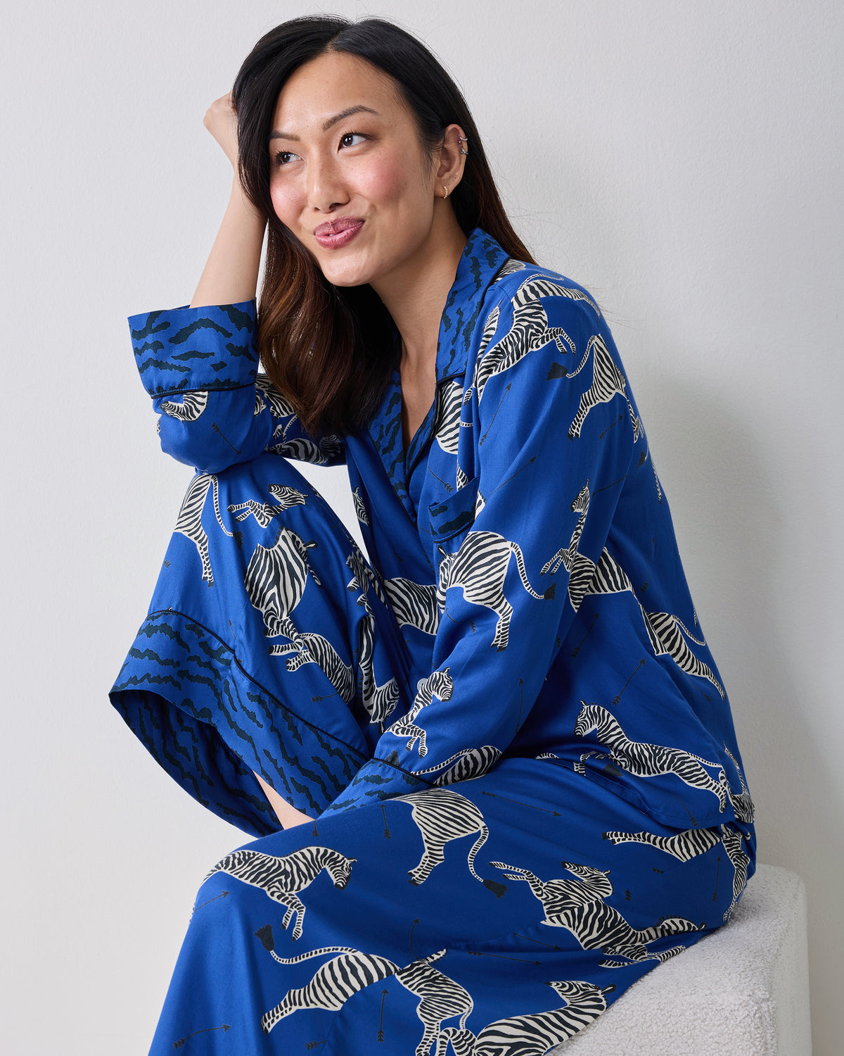 Seated person wearing a blue long-sleeve pajama set with a zebra print.