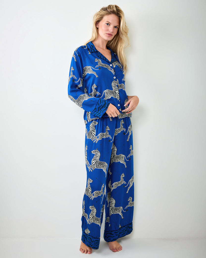 Person modeling a blue zebra-print long-sleeve pajama shirt and full-length pants, shown standing.