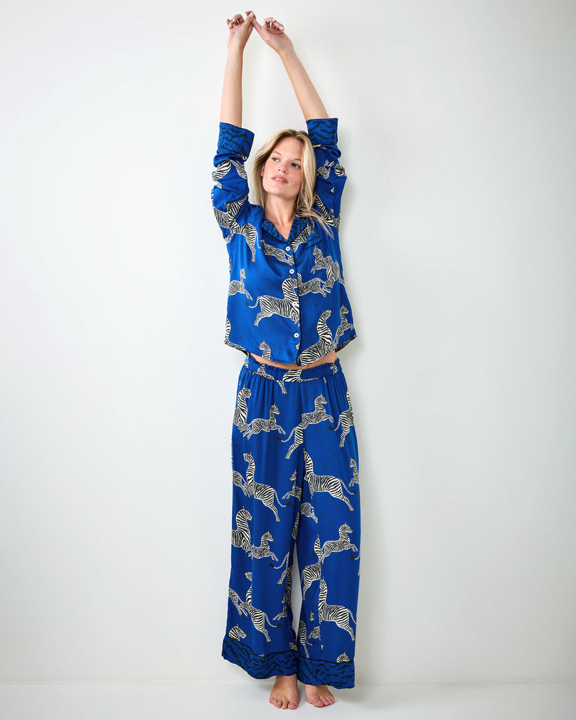 Person stretching while wearing a blue zebra-print pajama shirt and wide-leg pants.
