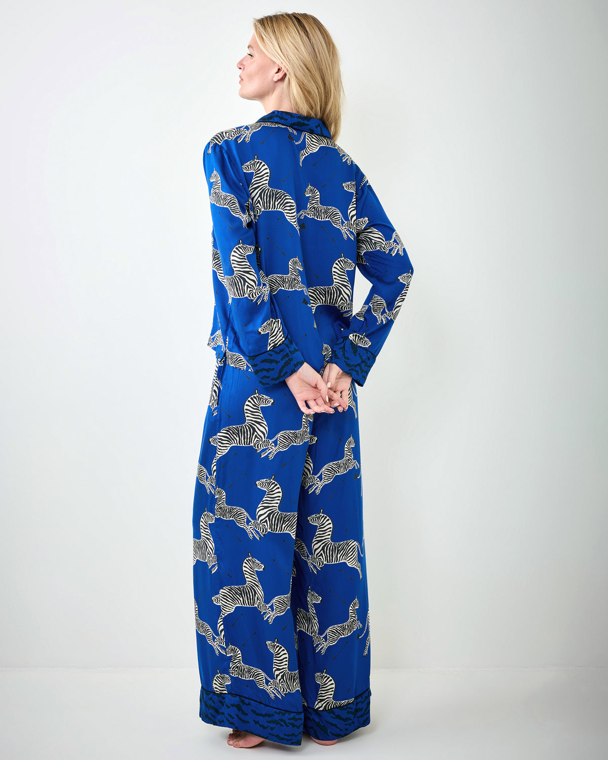 Back view of a person wearing a blue long-sleeve pajama set with a zebra print.