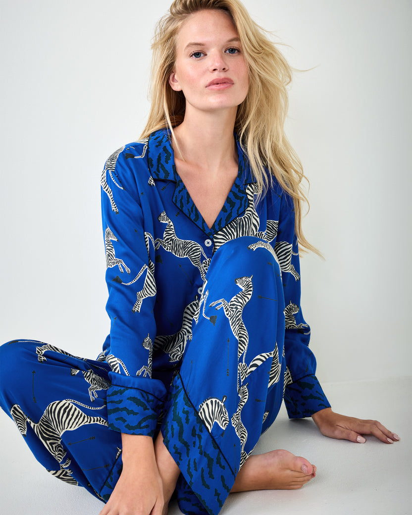 Person seated on the floor wearing a blue zebra-print long-sleeve pajama shirt and pants.