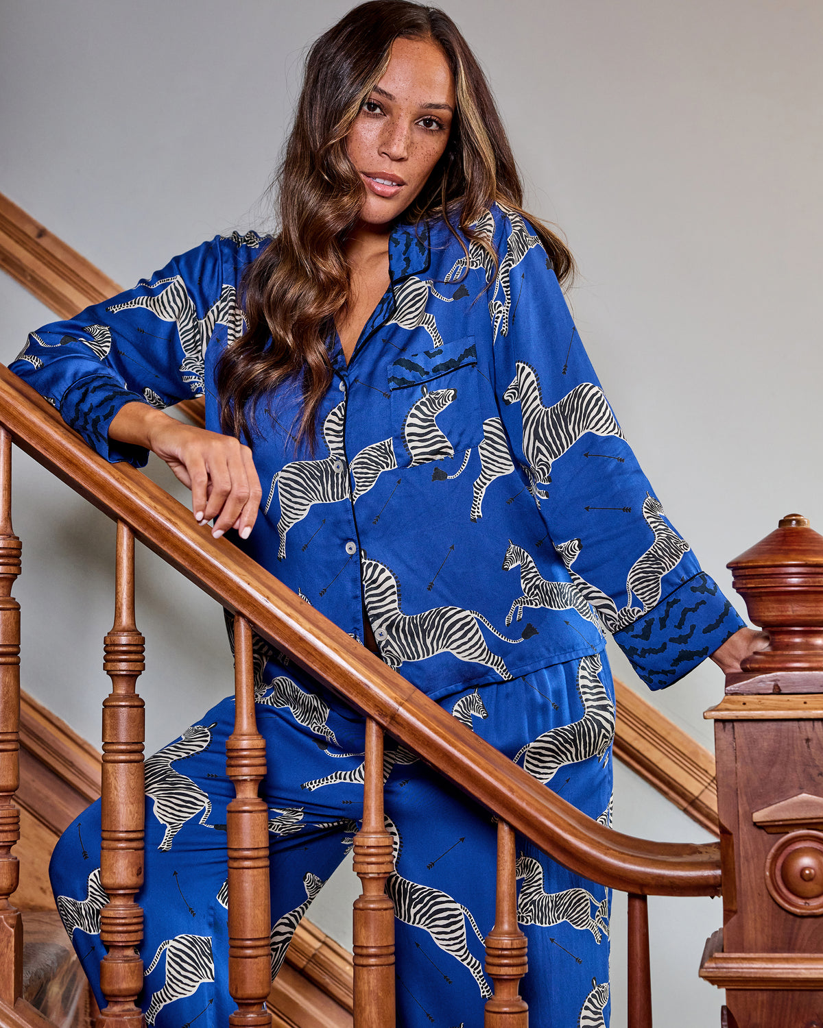 Person modeling a blue zebra-print long-sleeve pajama shirt and pants on a staircase.