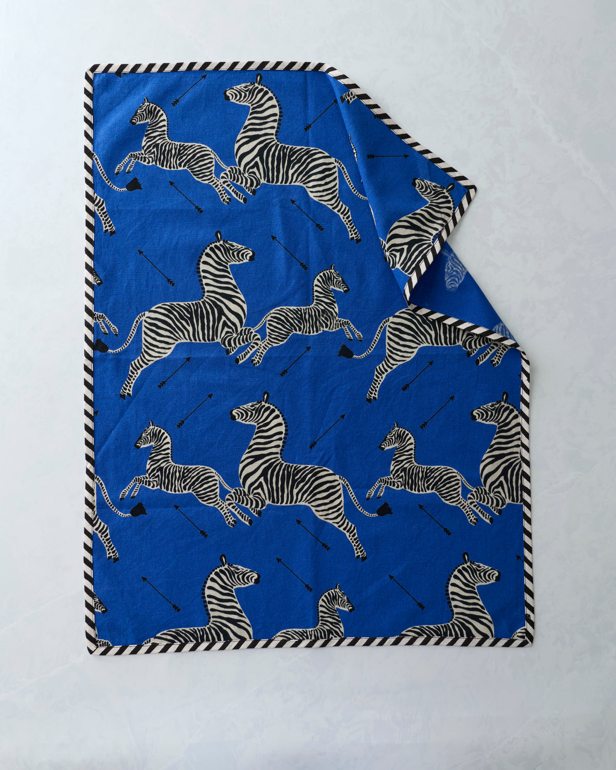 Blue tea towel with repeated zebra print and black-and-white striped edging, folded to show two towels
