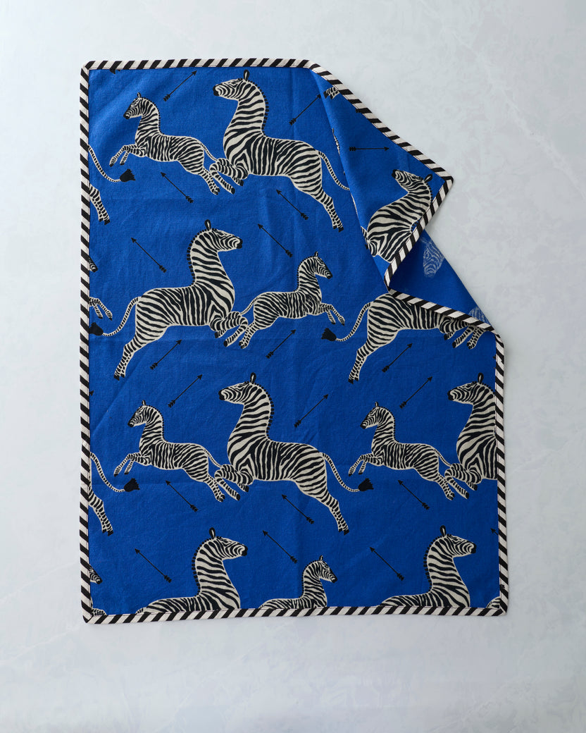 Blue tea towel with repeated zebra print and black-and-white striped edging, folded to show two towels