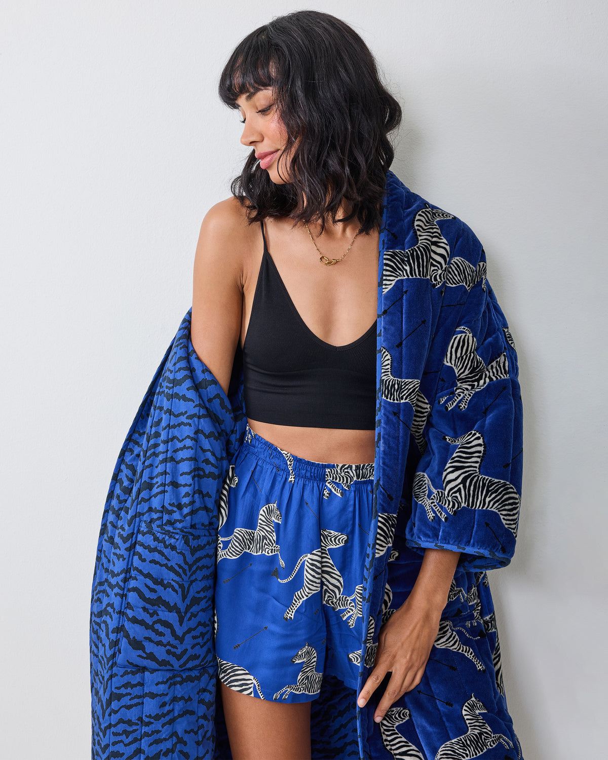 Person wearing a blue zebra-print quilted robe over a black top, shown from the waist up