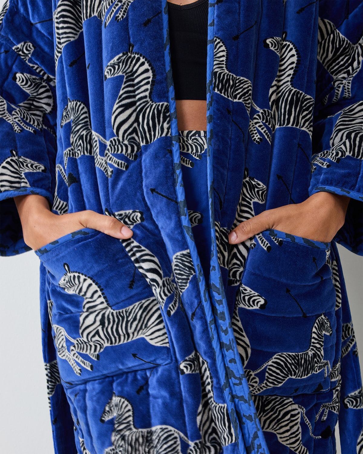 Close-up of a blue quilted robe with a zebra print and front pockets.
