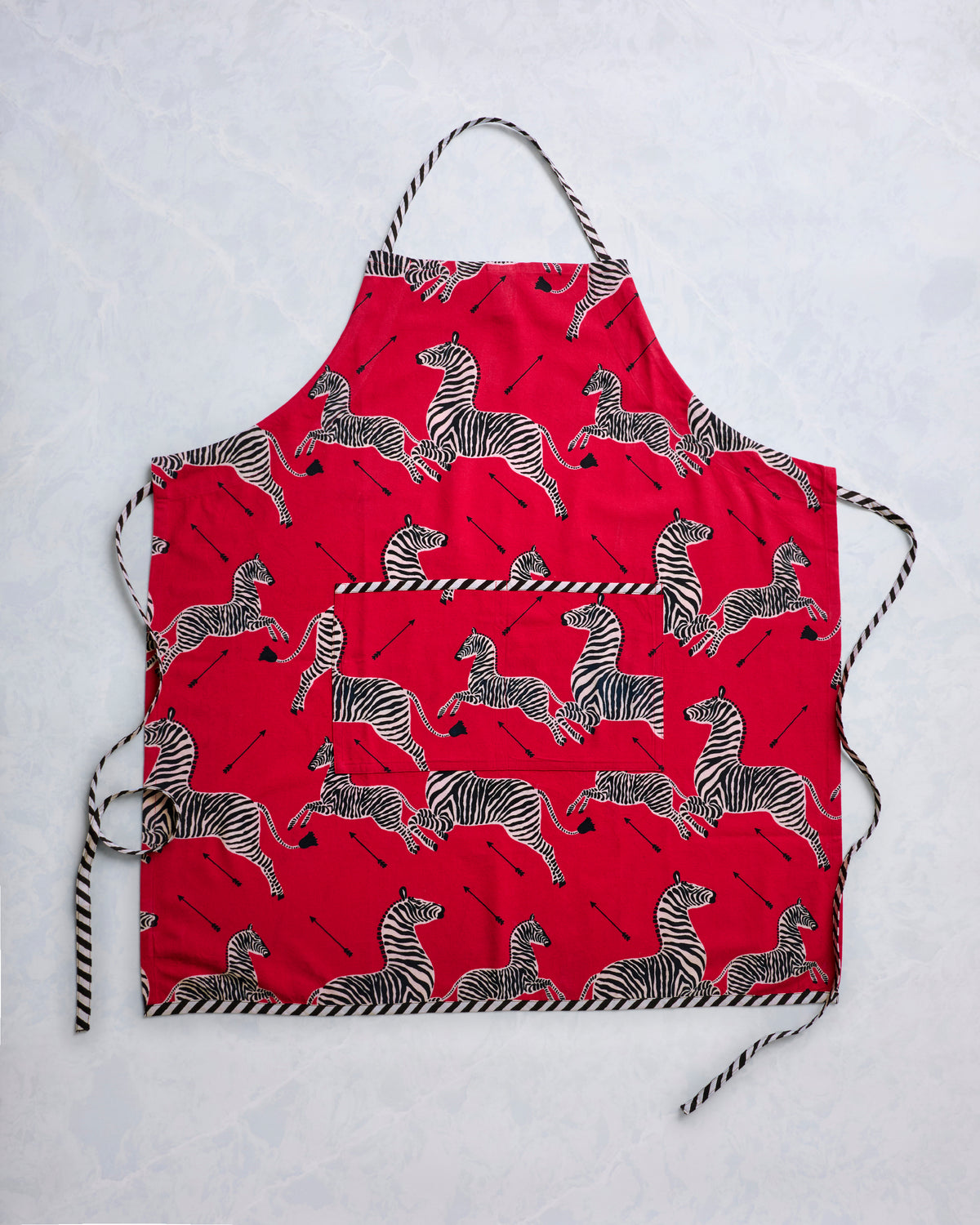 Red zebra-print apron with a front pocket and black-and-white striped neck and waist ties, shown flat.