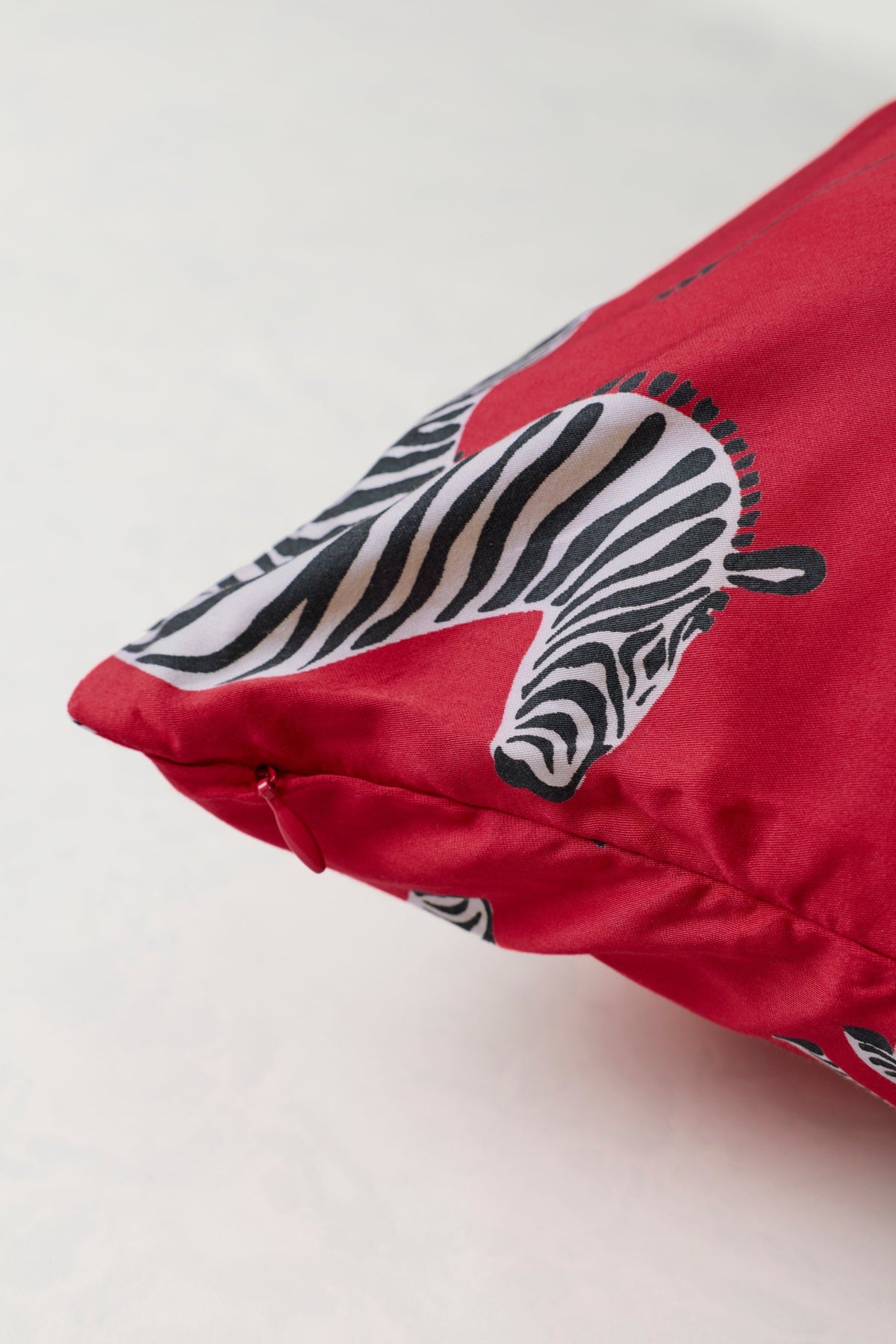 Close-up of a red satin pillowcase with a black-and-white zebra print and zipper closure.